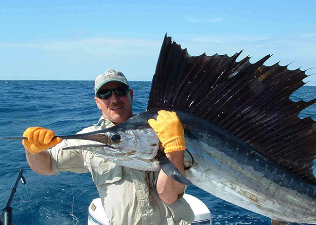 Cecil lifting a big fish he caught in the fishing charter trip.